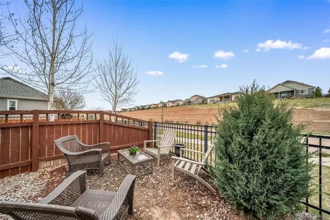 a view of a roof deck with table and chairs with wooden fence and plants