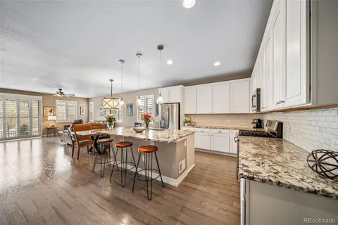 a kitchen with a sink a stove top oven a view dining table and chairs