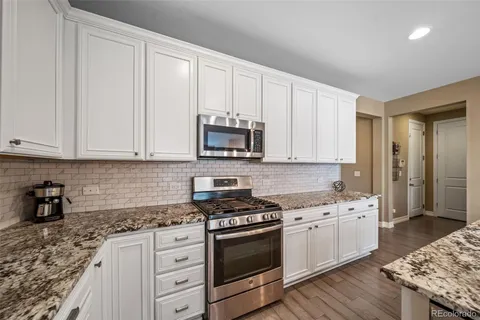 a kitchen with granite countertop white cabinets and stainless steel appliances
