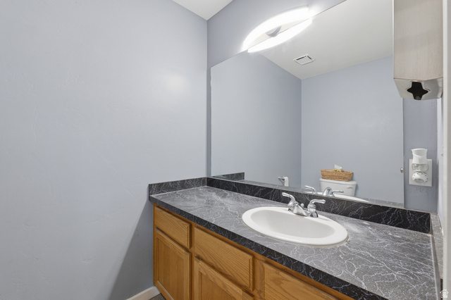 702 Alpine Highway Alpine, UT 84004 - Photo 59 of 83 Vanity with light wood-finish cabinetry, a black patterned countertop, and an integrated white oval sink with chrome fixtures