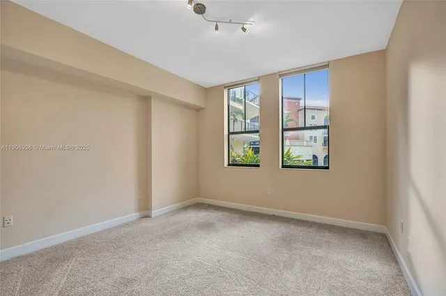 an empty room with windows and ceiling fan