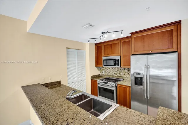 a kitchen with stainless steel appliances granite countertop a refrigerator a stove and a sink