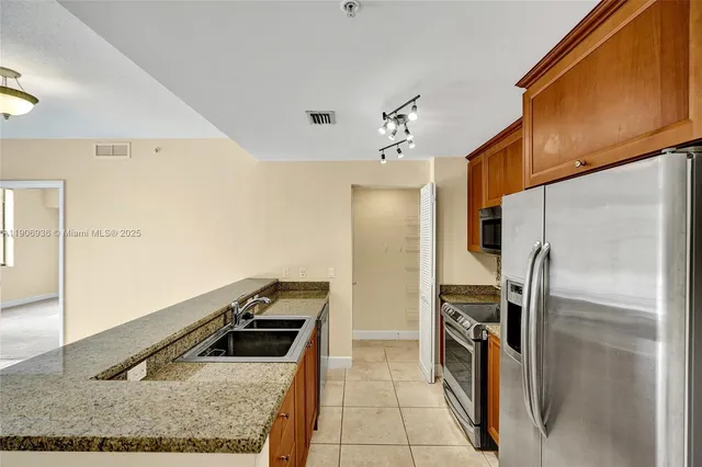 a kitchen with stainless steel appliances granite countertop a refrigerator a oven and a sink
