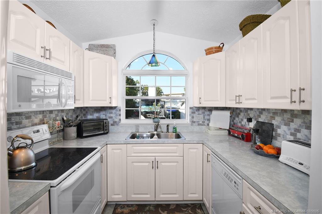 10725 South Ocean Drive, Unit 214 Jensen Beach, FL 34957 - Photo 20 of 90 a kitchen with white cabinets and white appliances