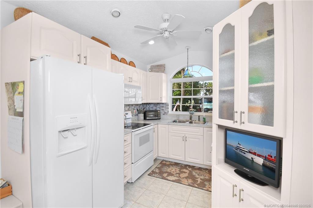 10725 South Ocean Drive, Unit 214 Jensen Beach, FL 34957 - Photo 21 of 90 a kitchen with white cabinets and white appliances