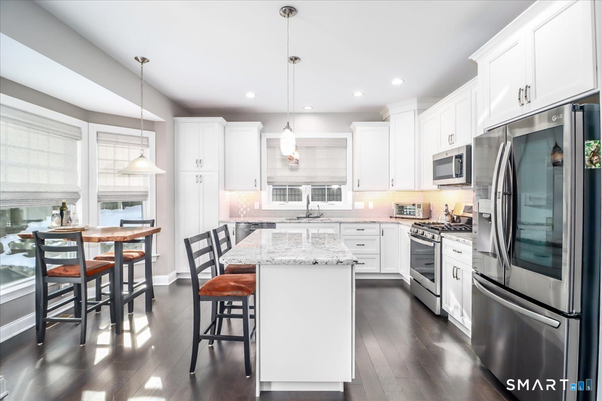 32 Hunting Ridge Lane, Unit 32 Bethel, CT 06801 - Photo 13 of 39 a kitchen with stainless steel appliances a refrigerator a stove a table and chairs with wooden floor