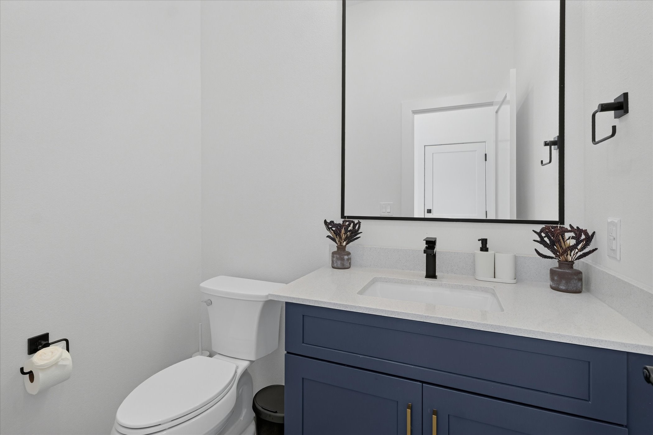 2000 Riverside Farms Road, Unit 8101 Austin, TX 78741 - Photo 11 of 41 This modern bathroom features a sleek design with a navy blue vanity, white countertop, and a black-framed mirror. It includes a toilet, contemporary fixtures, and minimalist decor, creating a clean and stylish space.