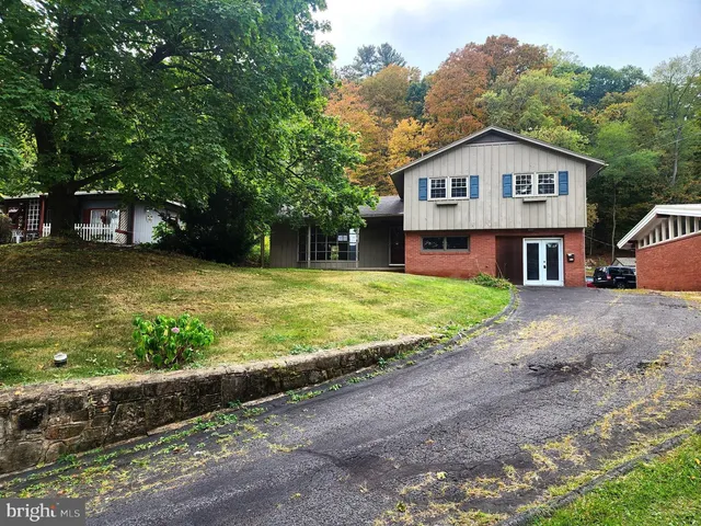 a view of a house with a yard and large tree