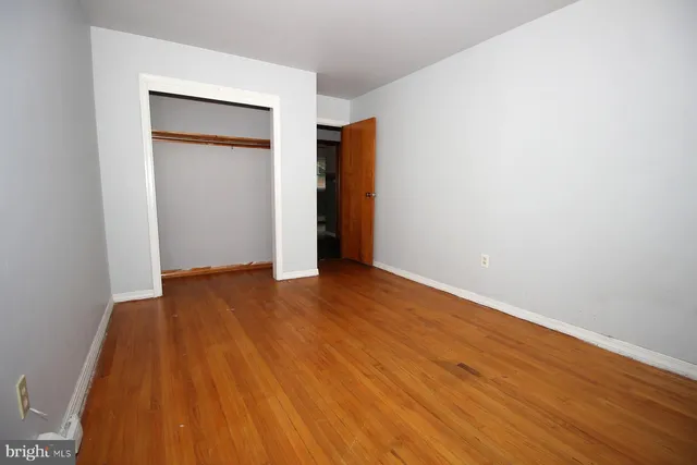 a view of an empty room with wooden floor and closet