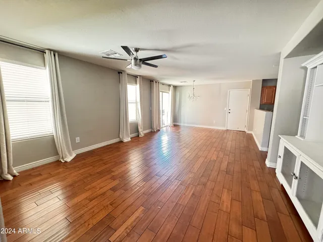 a view of a livingroom with wooden floor and a ceiling fan
