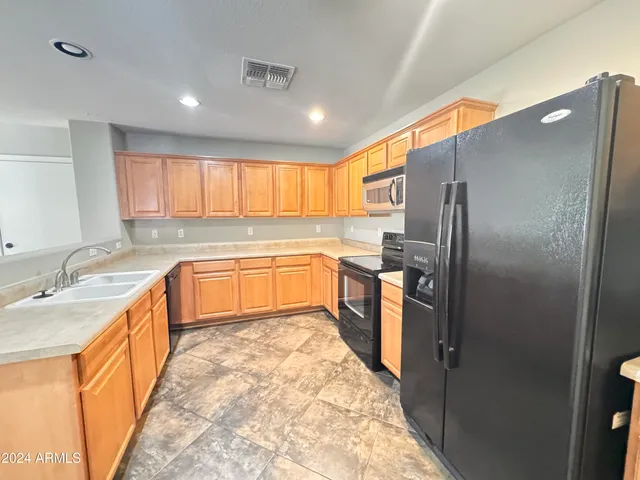 a large kitchen with stainless steel appliances granite countertop a sink stove and refrigerator