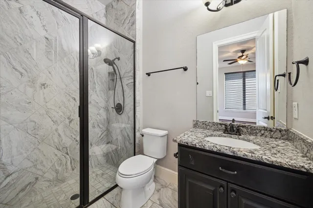 a bathroom with a granite countertop sink toilet and shower