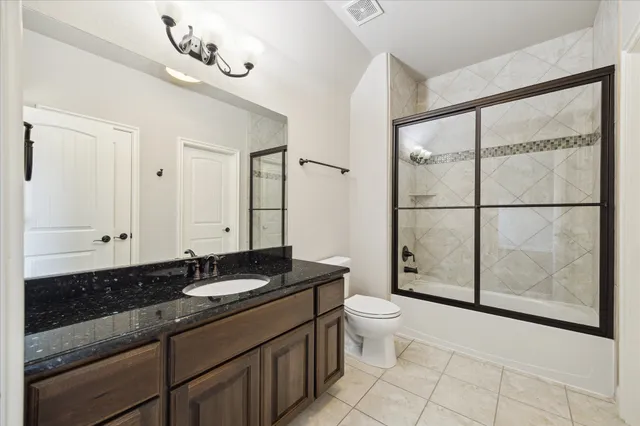 a bathroom with a granite countertop sink a toilet a mirror and shower
