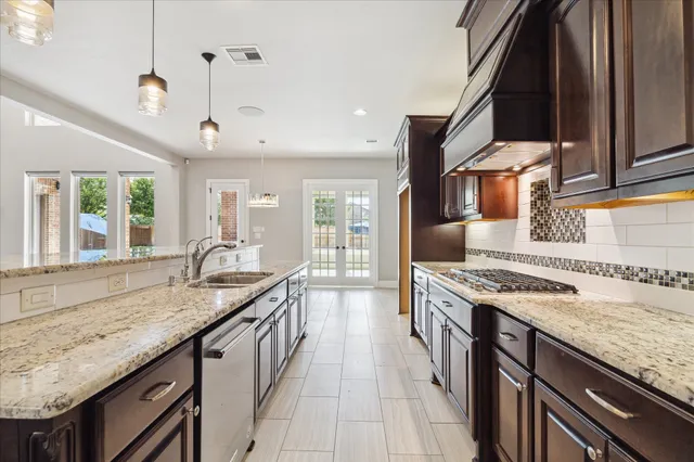 a kitchen with granite countertop stainless steel appliances a sink stove and cabinets