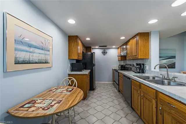 a large kitchen with stainless steel appliances a large counter top a stove a chimney a sink and a refrigerator