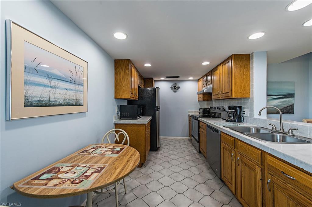 17 Bluebill Avenue, Unit 1102 Naples, FL 34108 - Photo 2 of 12 a large kitchen with stainless steel appliances a large counter top a stove a chimney a sink and a refrigerator
