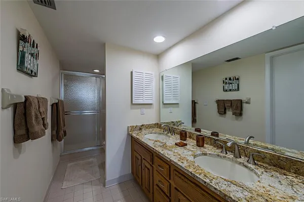 a bathroom with a granite countertop sink a mirror and shower
