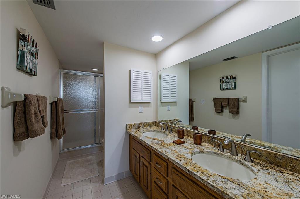 17 Bluebill Avenue, Unit 1102 Naples, FL 34108 - Photo 8 of 12 a bathroom with a granite countertop sink a mirror and shower