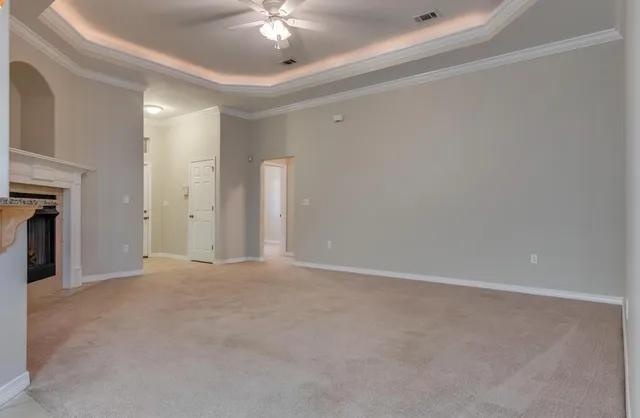 a view of an empty room with chandelier fan