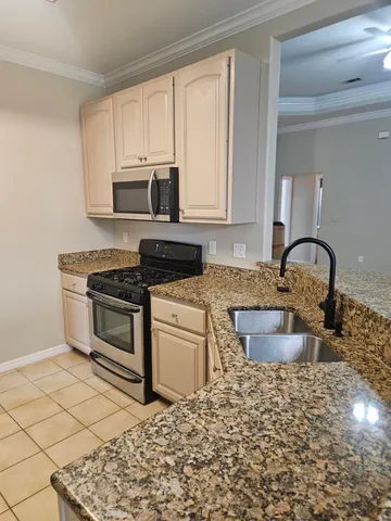 a kitchen with stainless steel appliances granite countertop a stove a sink and a microwave