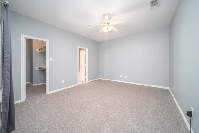 a view of an empty room with a chandelier fan