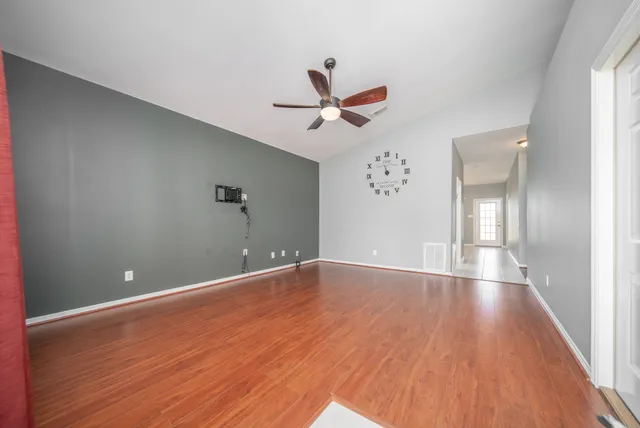 an empty room with wooden floor and windows