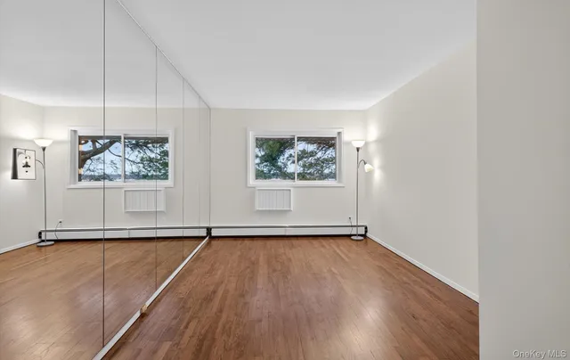 an empty room with wooden floor fan and windows