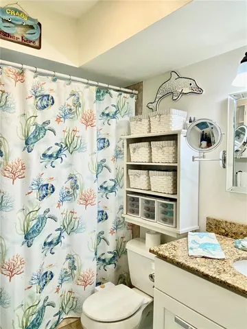 a bathroom with a granite countertop sink and a toilet