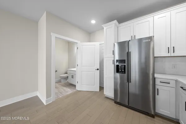a view of a kitchen with refrigerator and white cabinets