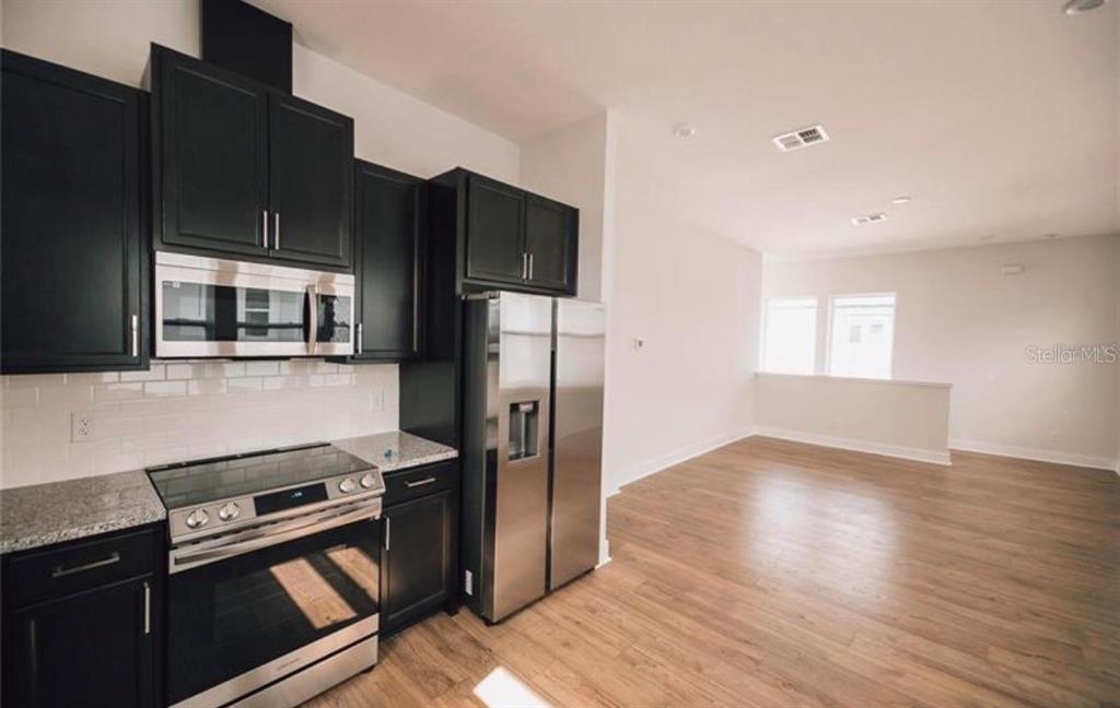 6824 Bridgman Street Orlando, FL 32827 - Photo 4 of 19 a kitchen with stainless steel appliances wooden cabinets and wooden floor
