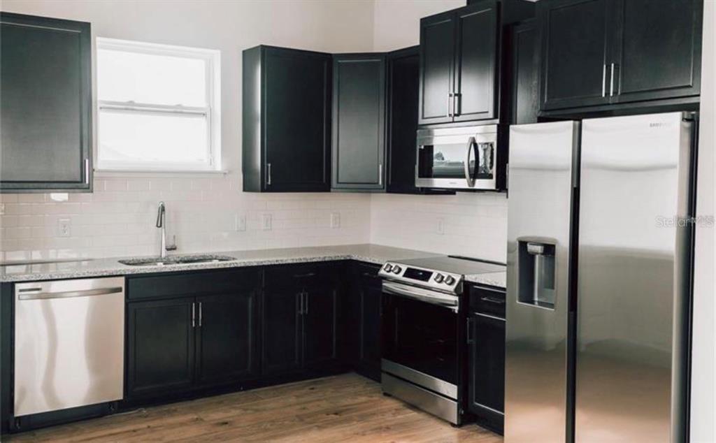 6824 Bridgman Street Orlando, FL 32827 - Photo 6 of 19 a kitchen with granite countertop stainless steel appliances and refrigerator