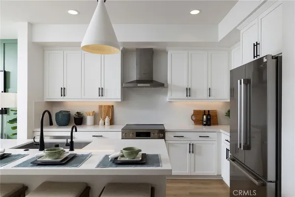 a kitchen with a dining table a sink and white cabinets