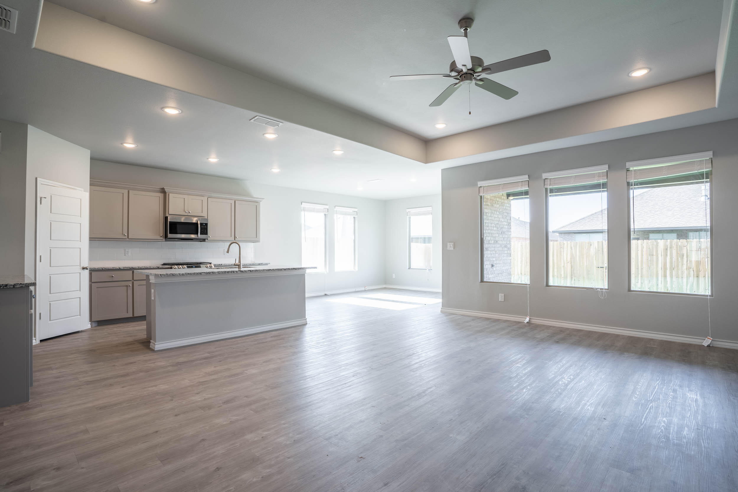 7602 60th Street Lubbock, TX 79407 - Photo 12 of 24 a view of an empty room with wooden floor and a kitchen