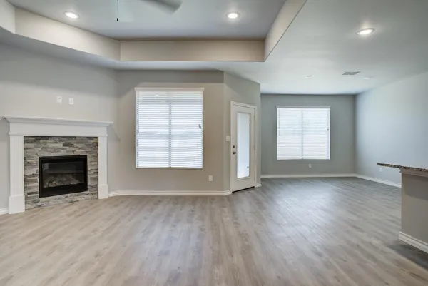 an empty room with wooden floor fireplace and windows