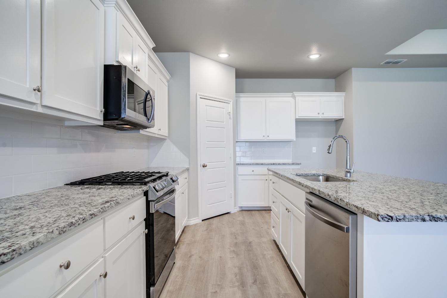 7602 60th Street Lubbock, TX 79407 - Photo 14 of 24 a kitchen with stainless steel appliances granite countertop a stove sink and cabinets