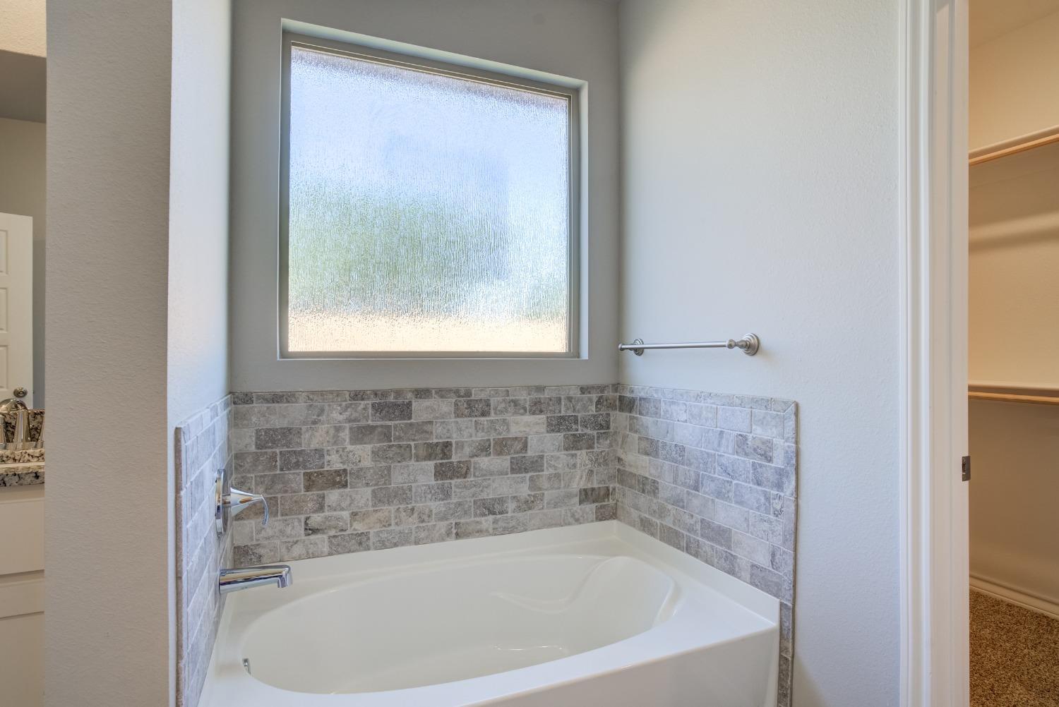 7602 60th Street Lubbock, TX 79407 - Photo 16 of 24 a bath tub sitting in a bathroom next to a window