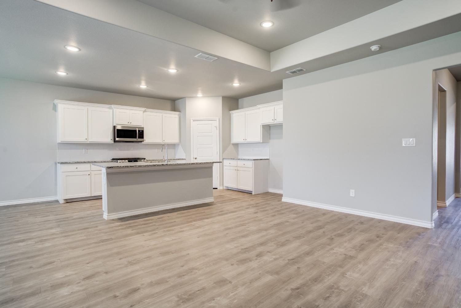 7602 60th Street Lubbock, TX 79407 - Photo 9 of 24 a kitchen with granite countertop white cabinets and stainless steel appliances