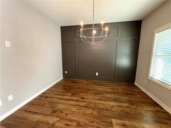 a view of an empty room with window and chandelier fan