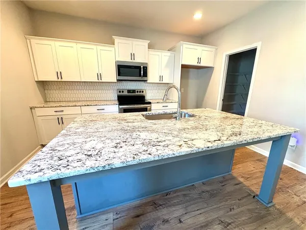 a kitchen with kitchen island granite countertop a sink stove and refrigerator