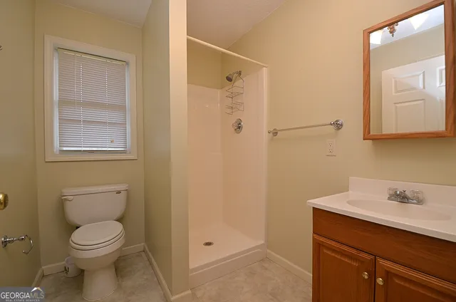 a bathroom with a toilet a sink a shower and mirror