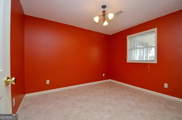an empty room with a chandelier fan and a window