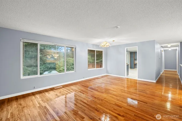 a view of an empty room with window and wooden floor
