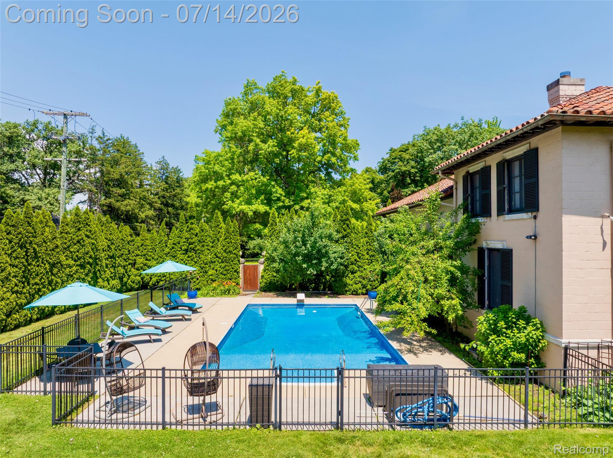 189 Cloverly Road Grosse Pointe, MI 48236 - Photo 79 of 96 Rectangular swimming pool with a surrounding concrete patio, secured by a black metal fence