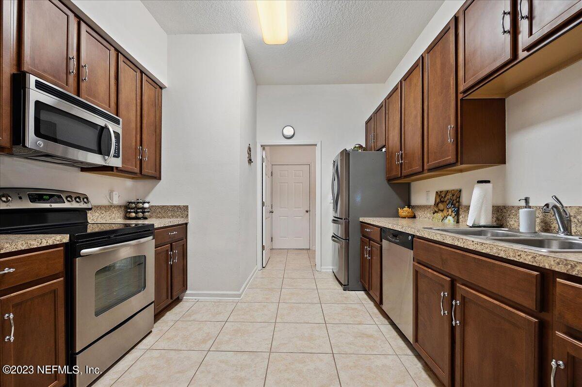 605 Golden Lake Loop St. Augustine, FL 32084 - Photo 9 of 20 a kitchen with stainless steel appliances granite countertop a stove top oven a sink dishwasher and a refrigerator with wooden cabinets