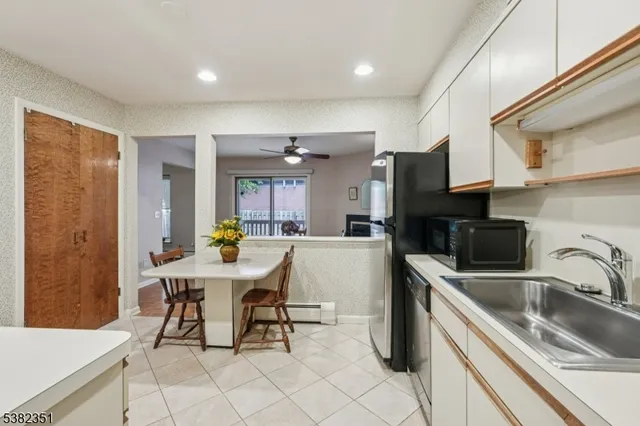 a kitchen with stainless steel appliances a sink a stove a refrigerator cabinets and dining table