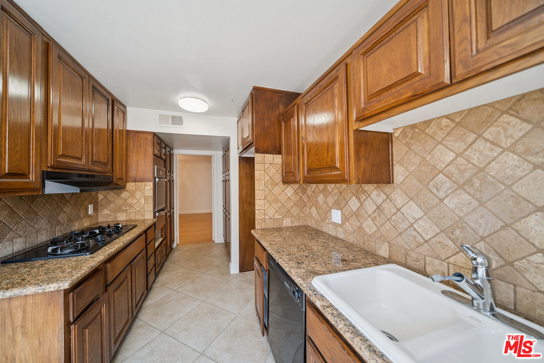 1508 Greenfield Avenue, Unit 206 Los Angeles, CA 90025 - Photo 11 of 31 a kitchen with granite countertop a sink stove and cabinets