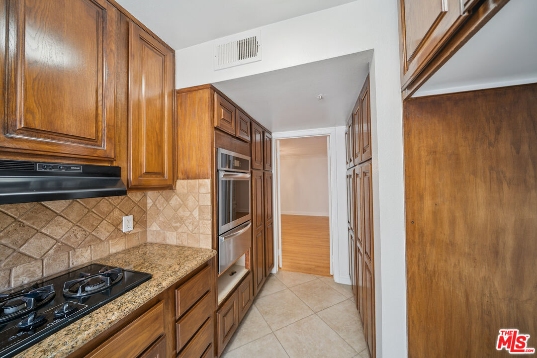 1508 Greenfield Avenue, Unit 206 Los Angeles, CA 90025 - Photo 12 of 31 a kitchen with granite countertop a refrigerator and a stove top oven