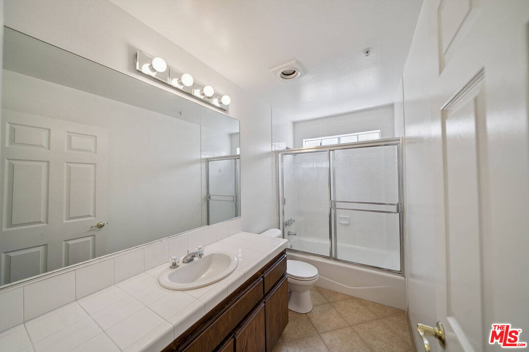 1508 Greenfield Avenue, Unit 206 Los Angeles, CA 90025 - Photo 20 of 31 a bathroom with a granite countertop sink a toilet and shower