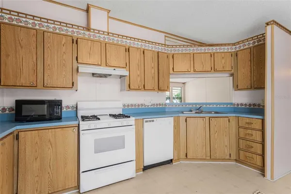 a kitchen with granite countertop a sink stove and cabinets