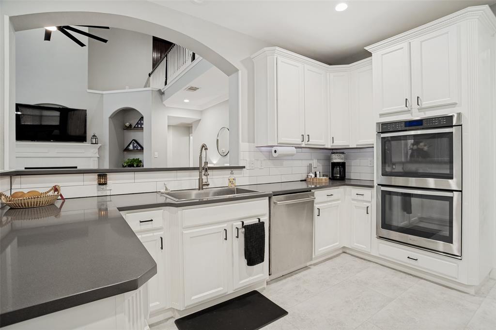 1612 Coventry Lane Allen, TX 75002 - Photo 25 of 39 Spacious kitchen featuring white cabinetry, gray countertops, stainless steel appliances, a subway tile backsplash, and light-toned flooring